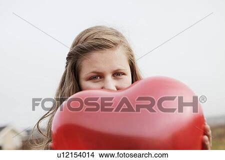 Picture - Girl holding heart-shaped balloon. Fotosearch