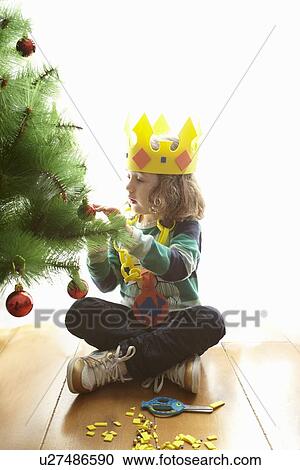 Stock Image - Girl in crown decorating Christmas tree. Fotosearch