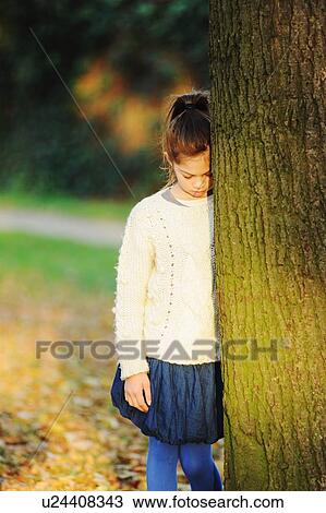 Girl leaning on tree in park View Large Photo Image Stock Image - Girl leaning on tree in park. Fotosearch