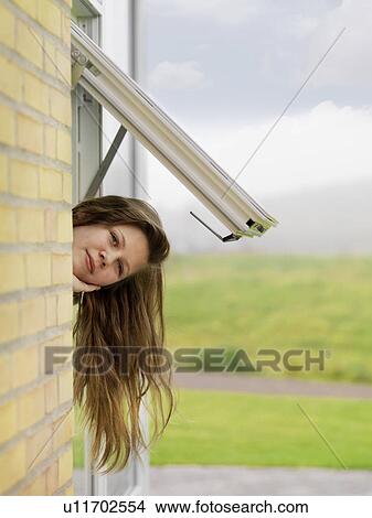 Picture - Girl peering outside window. Fotosearch