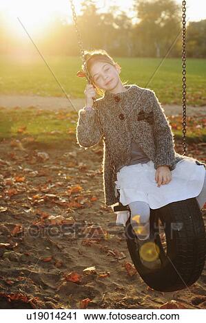 Girl playing on tire swing in park View Large Photo Image Stock Image - Girl playing on tire swing in park. Fotosearch
