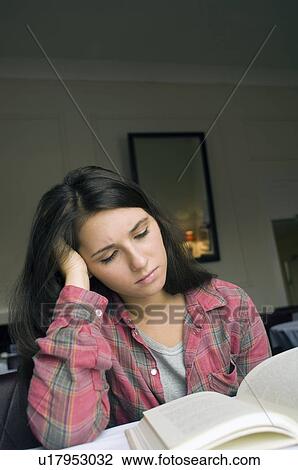 Stock Image - Girl reading book indoors. Fotosearch