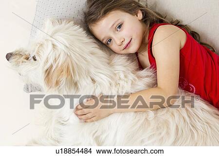 Picture - Girl relaxing in bed with dog. Fotosearch