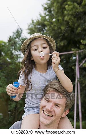 Stock Image - Girl with bubbles on fathers shoulders. Fotosearch