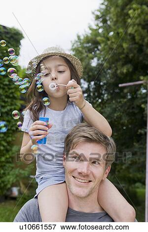 Girl with bubbles on fathers shoulders View Large Photo Image Stock Photo - Girl with bubbles on fathers shoulders. Fotosearch