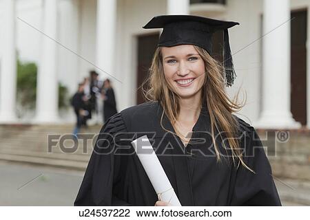 Stock Image - Graduate with her degree on campus. Fotosearch