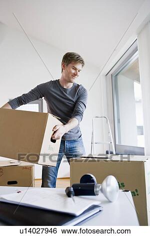 Man carrying cardboard boxes in house View Large Photo Image Stock Photograph - Man carrying cardboard boxes in house. Fotosearch