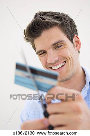 Stock Image - Man cutting up credit card. Fotosearch