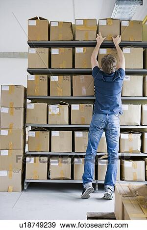 Stock Photo - Man filing cardboard boxes in storage. Fotosearch
