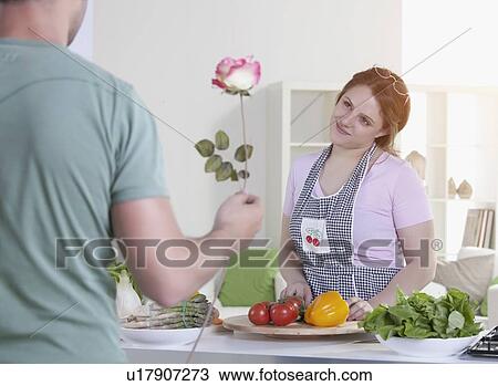 Man giving rose to cooking girlfriend View Large Photo Image Stock Image - Man giving rose to cooking girlfriend. Fotosearch