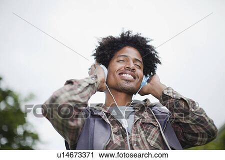 Stock Image - Man listening to headphones outdoors. Fotosearch
