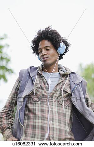 Stock Image - Man listening to headphones outdoors. Fotosearch