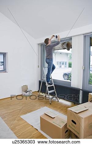 Stock Image - Man painting room in new house. Fotosearch