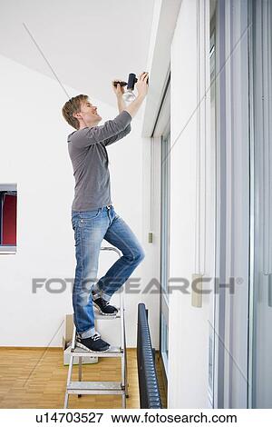 Stock Photo - Man painting room in new house. Fotosearch