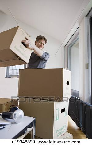 Man stacking cardboard boxes in house View Large Photo Image Stock Photo - Man stacking cardboard boxes in house. Fotosearch