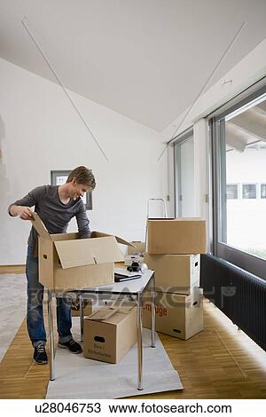 Stock Image - Man unpacking cardboard boxes. Fotosearch