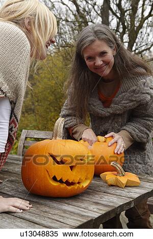 Stock Photography - Mother and daughter carving pumpkins. Fotosearch