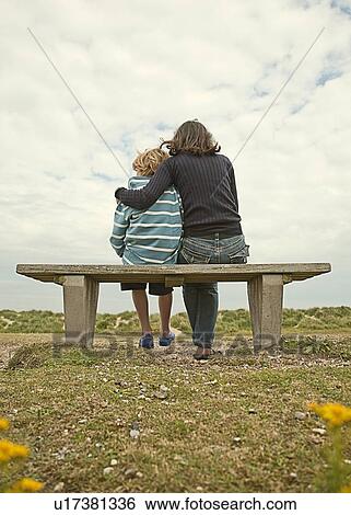 Mother and son sitting on bench outdoors View Large Photo Image Stock Photograph - Mother and son sitting on bench outdoors. Fotosearch