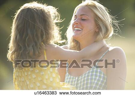 Stock Image - Mother holding daughter outdoors. Fotosearch