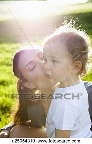 Stock Photo - Mother kissing toddler in park. Fotosearch