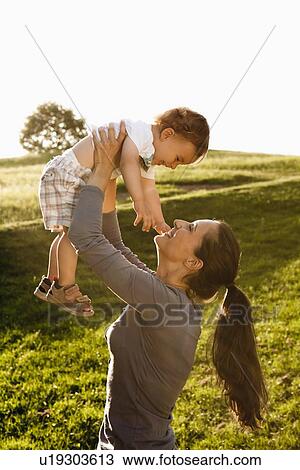 Mother playing with toddler in park View Large Photo Image Stock Image - Mother playing with toddler in park. Fotosearch