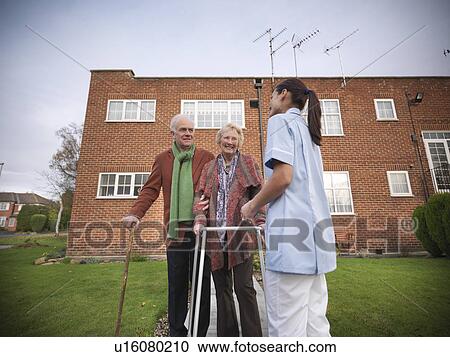 Stock Image - Nurse and older couple walking outdoors. Fotosearch