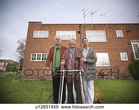 Stock Photo - Nurse and older couple walking outdoors. Fotosearch
