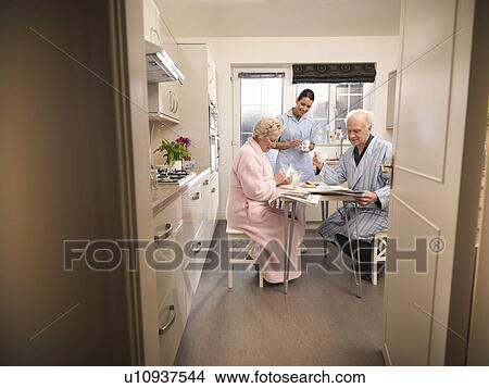 Nurse bringing older couple coffee View Large Photo Image Picture - Nurse bringing older couple coffee. Fotosearch