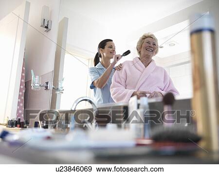 Stock Photo - Nurse helping older woman brush hair. Fotosearch
