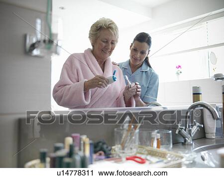 Nurse helping older woman brush teeth View Large Photo Image Stock Image - Nurse helping older woman brush teeth. Fotosearch