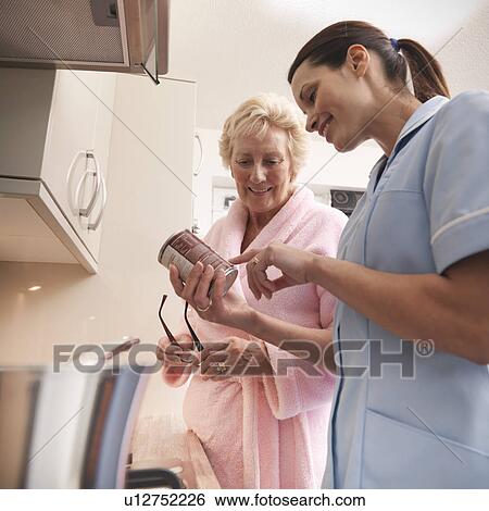 Stock Photograph - Nurse reading label for older woman. Fotosearch