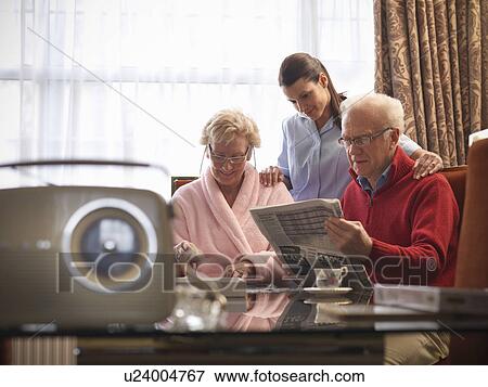 Stock Photo - Nurse reading with older couple. Fotosearch