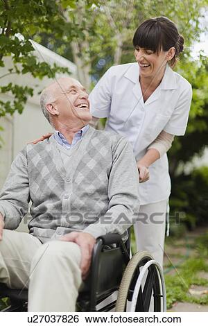 Stock Photograph - Nurse wheeling older patient outdoors. Fotosearch