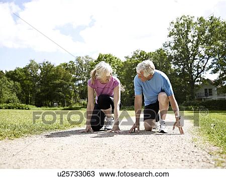 Stock Image - Older couple crouched in start position. Fotosearch