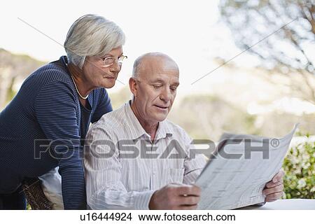 Older couple reading newspaper outdoors View Large Photo Image Picture - Older couple reading newspaper outdoors. Fotosearch