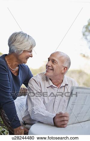 Stock Image - Older couple reading newspaper outdoors. Fotosearch