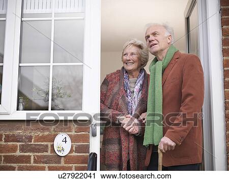 Stock Image - Older couple standing in doorway. Fotosearch