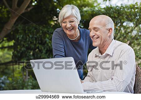 Older couple using laptop outdoors View Large Photo Image Stock Photo - Older couple using laptop outdoors. Fotosearch