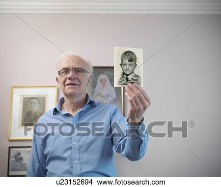 Picture - Older man holding old photograph. Fotosearch