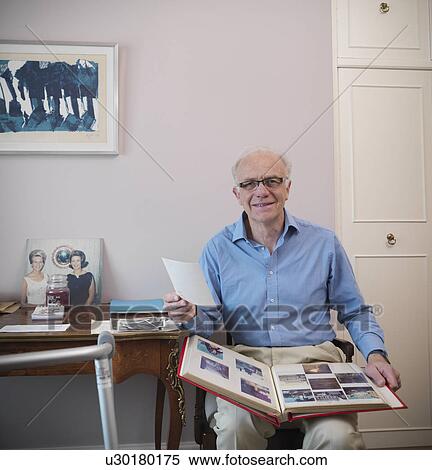 Older man looking through photo album View Large Photo Image Stock Photography - Older man looking through photo album. Fotosearch