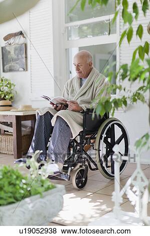 Stock Photo - Older man reading in wheelchair. Fotosearch