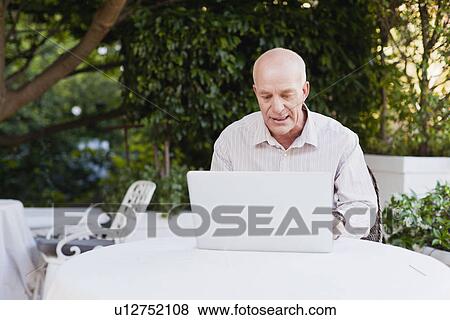 Older man using laptop outdoors View Large Photo Image Stock Photo - Older man using laptop outdoors. Fotosearch