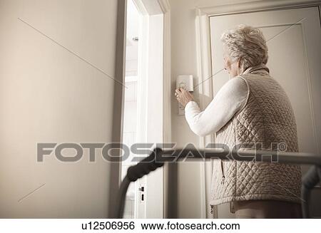 Stock Photograph - Older woman adjusting heating in house. Fotosearch