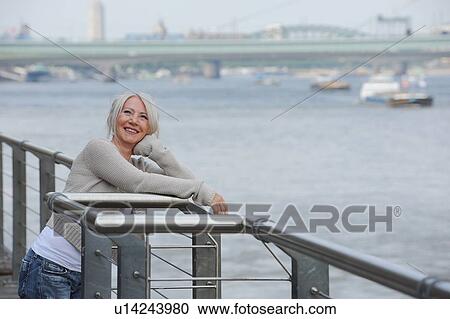 Stock Image - Older woman admiring urban port. Fotosearch