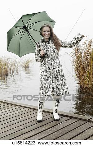 Stock Image - Older woman carrying umbrella on dock. Fotosearch