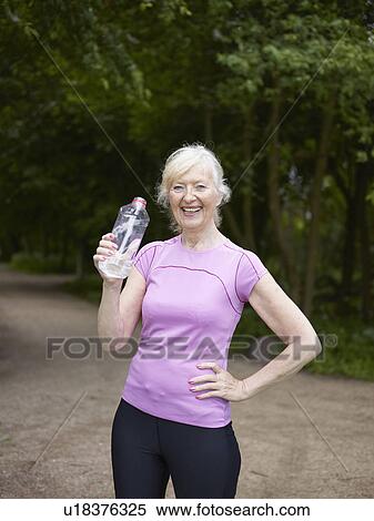 Stock Photography - Older woman drinking from water bottle. Fotosearch