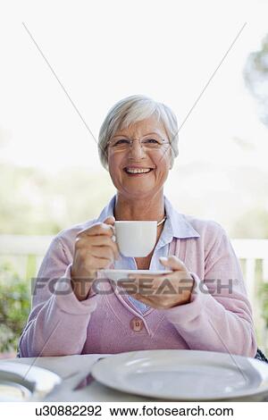 Stock Image - Older woman having cup of coffee. Fotosearch