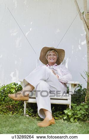 Picture - Older woman relaxing in backyard. Fotosearch