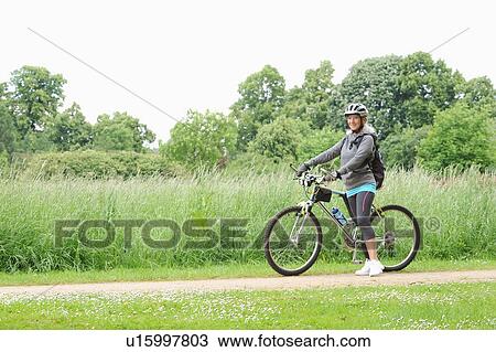 Older woman riding bicycle on rural road View Large Photo Image Stock Image - Older woman riding bicycle on rural road. Fotosearch