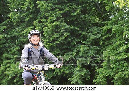 Older woman riding bicycle on rural road View Large Photo Image Stock Photo - Older woman riding bicycle on rural road. Fotosearch